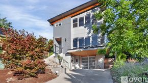 Portland apartment for rent - A modern house with a grey exterior and a brown roof is surrounded by greenery and has a sign that says "available".