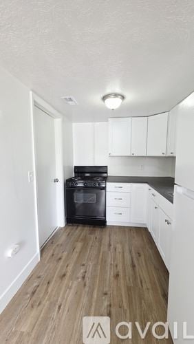 Salt Lake City house for rent - A kitchen with white cabinets and a black stove top oven.
