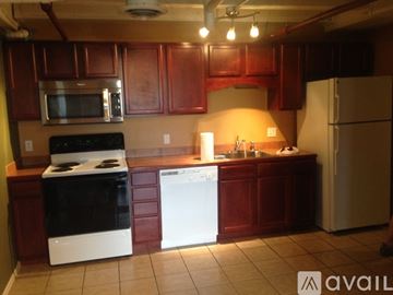 Pueblo apartment for rent - A kitchen with a black stove top oven, a white dishwasher, and a white refrigerator.