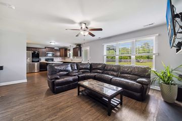 Jacksonville house for rent - A black leather sectional sofa with a glass coffee table in the middle of a living room.