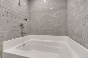 Spartanburg house for rent - A white bathtub in a bathroom with grey tiled walls.