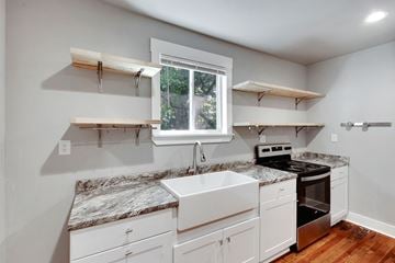 Spartanburg house for rent - A kitchen with white cabinets and a marble countertop.