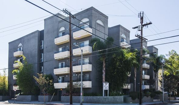 Los Angeles apartment for rent - A grey apartment building with balconies and trees in front.