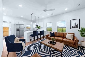 Greenville apartment for rent - A modern living room with a brown leather couch and a blue patterned rug.