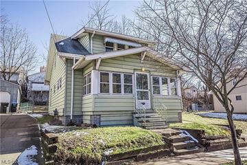 Akron house for rent - A green house with a black roof and a white door.