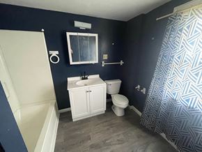 Akron house for rent - A bathroom with a white sink and toilet, a window, and a shower curtain.