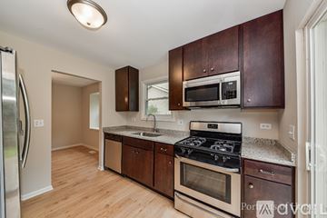 Aurora house for rent - A kitchen with dark wood cabinets and stainless steel appliances.