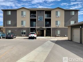 Box Elder apartment for rent - A multi-story apartment building with cars parked in front.