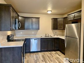 Box Elder apartment for rent - A kitchen with dark wood cabinets and a stainless steel refrigerator.