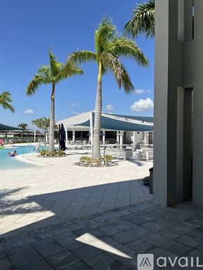 Parrish house for rent - A pool area with palm trees and a building in the background.