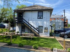 Charlottesville apartment for rent - A white house with a black staircase and a picnic table in front.