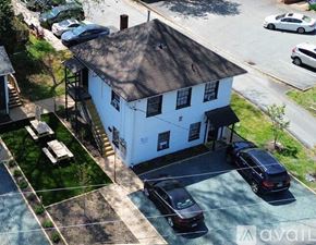 Charlottesville apartment for rent - A white building with a black roof is surrounded by a parking lot.