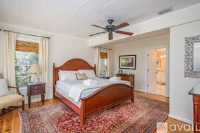 Tybee Island house for rent - A bedroom with a large bed and a ceiling fan.