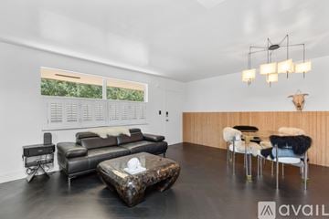 Miami house for rent - A living room with a black leather couch and a wooden coffee table.