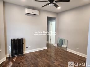 Chicago apartment for rent - A room with a fan, air conditioner, and wood flooring.
