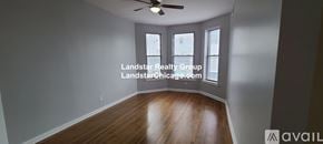 Chicago apartment for rent - A spacious room with wooden floors and a ceiling fan.