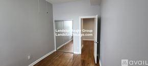 Chicago apartment for rent - A room with a wooden floor and white walls, with a doorway leading to another room.