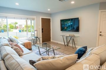 Los Angeles house for rent - A living room with a large couch and a flat screen TV mounted on the wall.