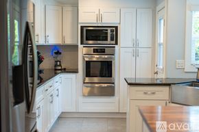 Los Angeles house for rent - A kitchen with white cabinets and a black countertop.