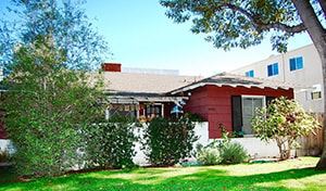 Valley Village apartment for rent - A red house with a white fence and green bushes in front.