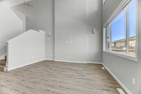 Spruce Grove apartment for rent - A spacious room with light wood flooring and a staircase on the left side.