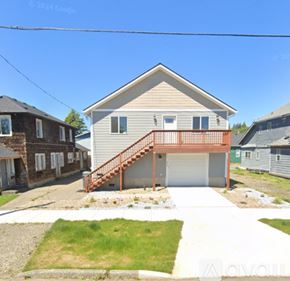 Hoquiam apartment for rent - A house with a garage and a deck is surrounded by other houses.