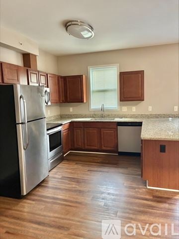 Cincinnati apartment for rent - A kitchen with wooden cabinets and a black refrigerator.