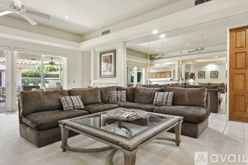 Indian Wells house for rent - A spacious living room with a large sectional sofa and a glass coffee table.