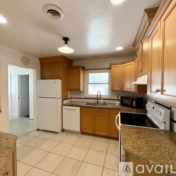 Sarasota house for rent - A kitchen with wooden cabinets and white appliances.