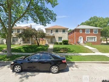 Milwaukee apartment for rent - A black car is parked on a sunny day in front of a house.