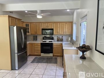 Indian Wells house for rent - A living room with a television on the wall and a view of a pool and trees outside the window.