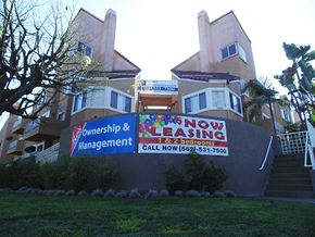 Paramount apartment for rent - a now leasing management sign in front of an apartment building