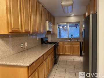Pomona house for rent - A kitchen with wooden cabinets and a black refrigerator.