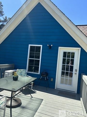Apex house for rent - A small white house with a brown roof and a wooden fence.