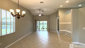 West Palm Beach house for rent - A spacious room with a chandelier, ceiling fan, and sliding glass doors.