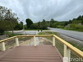 North Creek apartment for rent - A wooden deck overlooks a road with a cloudy sky above.