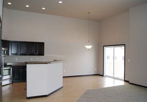 West Fargo townhouse for rent - an empty living room with a kitchen and a door