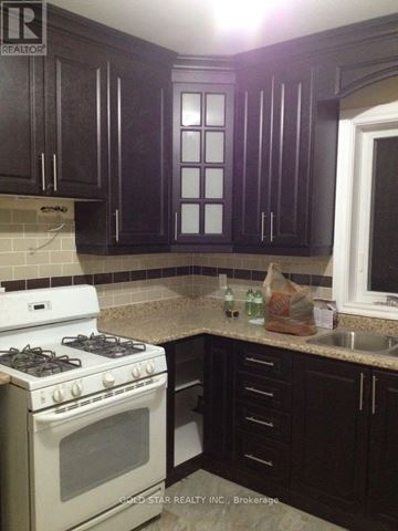 Oshawa (Central) house for rent - A kitchen with dark brown cabinets and a white stove top oven.