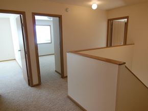 Moorhead townhouse for rent - a living room with a staircase and a hallway with a door to a bedroom