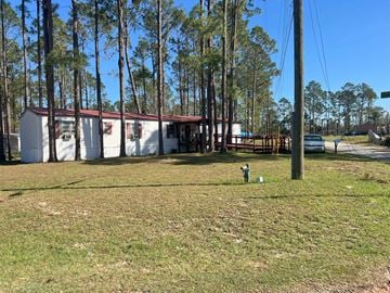 Valdosta apartment for rent - A grassy area with a building and trees in the background.