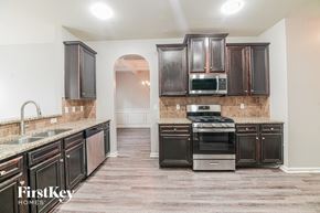 Newnan house for rent - A kitchen with dark wood cabinets and a stainless steel oven.
