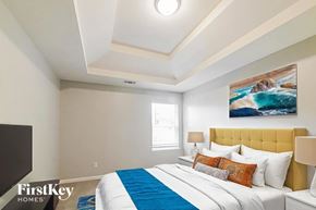 Newnan house for rent - A bedroom with a bed, a painting on the wall, and a window.