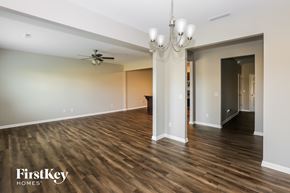 Statesville house for rent - A spacious room with wooden floors and a ceiling fan.