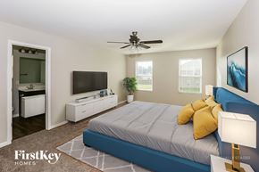 Statesville house for rent - A bedroom with a bed, a television, a ceiling fan, and a lamp.