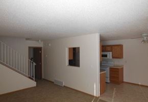 Moorhead townhouse for rent - an empty living room with a kitchen and a staircase