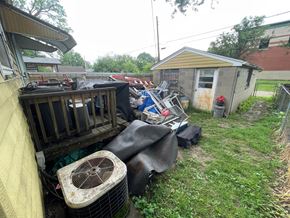Louisville house for rent - A cluttered yard with a shed and a fan.