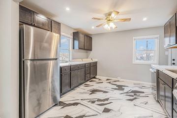 Gary house for rent - A modern kitchen with a stainless steel refrigerator and a ceiling fan.