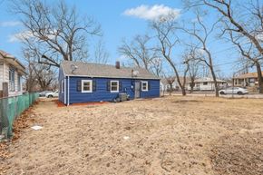 Gary house for rent - A blue house with a white fence and bare trees in the background.