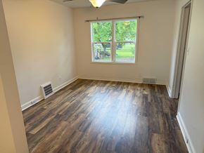 Wausau apartment for rent - A room with wooden flooring and a window showing a view of a park.