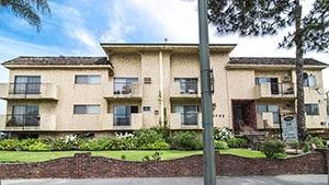 Los Angeles apartment for rent - A beige building with a black roof and a grey pole in front.